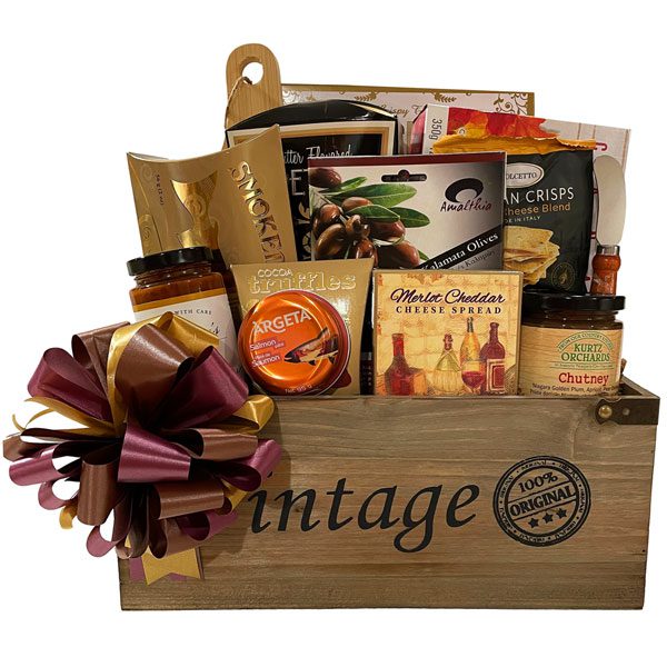 Bon Apetit Gift Basket-smoked salmon, a large box of appetizer crackers, bamboo cutting board, cheese knife, butter pretzels, maple cookies, olives, Tuscan crisps, antipasto, salmon pate, merlot cheddar cheese and a jar of chutney.